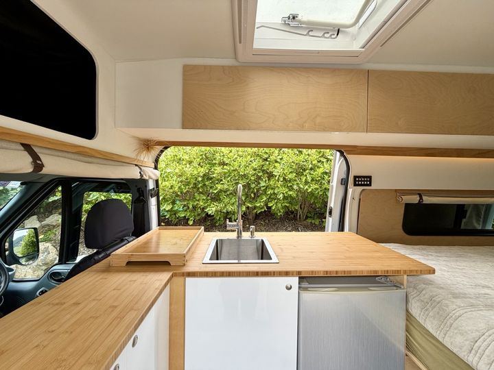 Galley with the roof hatch propped open and overhead lockers along the wall