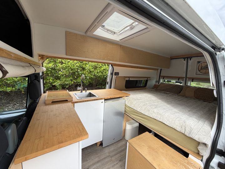 Bamboo galley on the left and the made-up bed across the back of the van