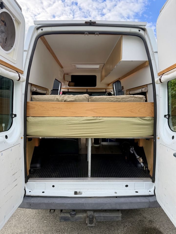 Rear doors open showing the fixed bed and the storage garage below it